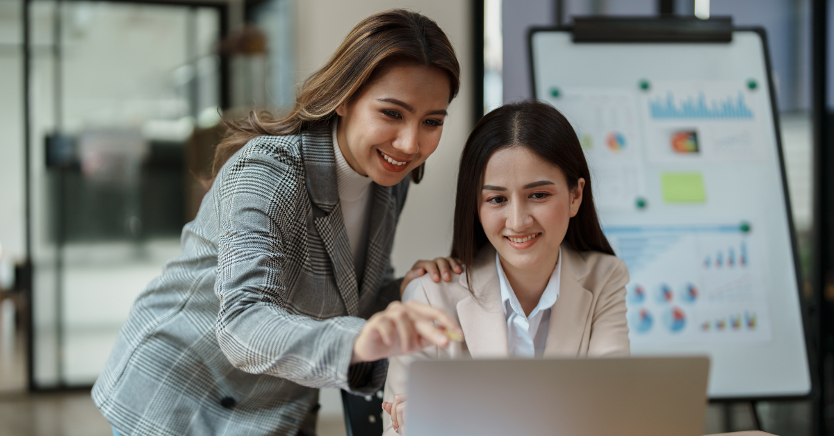 Two co-workers look a data on a computer screen.