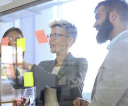 Team collaborating with sticky notes on a glass board for local SEO strategy planning.