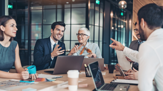 A group of co-workers are meeting in a boardroom and discussing good results.