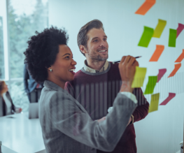 Two marketing professionals writing on sticky notes, brainstorming SEO ideas.