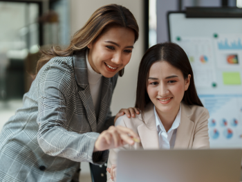 Two co-workers look a data on a computer screen.