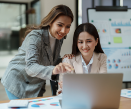 Two SEO professionals analyzing data on a laptop with charts and graphs on the table.