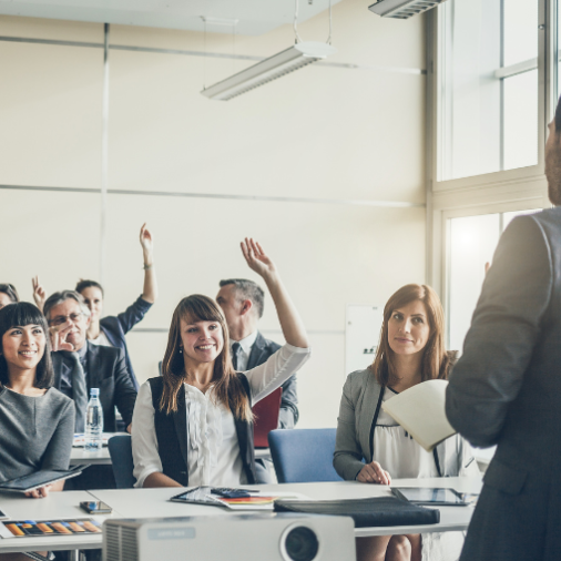 A group of business professionals raising hands during an Adobe Experience Cloud interactive training session.