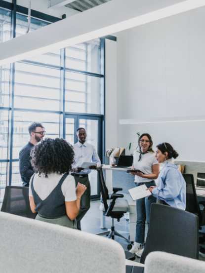 A diverse team of professionals standing and collaborating in a modern office space.